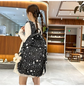 Close-up of stylish black star print backpack with cute bunny plush keychain in a cafe