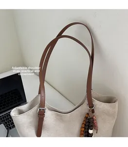Detail of adjustable shoulder strap with metal buckle on minimalist suede tote bag