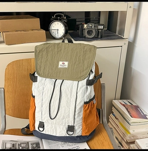 Multi-colored patchwork backpack in nylon displayed on a wooden chair with books