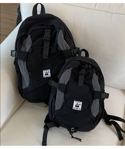 Detail view of large and small black-grey commuter backpacks with penguin logo on a sofa