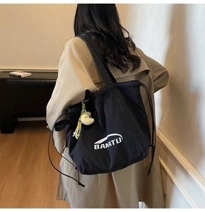 Detail der schwarzen Nylon-Kordelzug-Tasche mit BANATU-Logo und flauschigem Mondanhänger