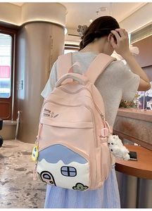 Detail of pink nylon school backpack with house embroidery and white plush puppy charm