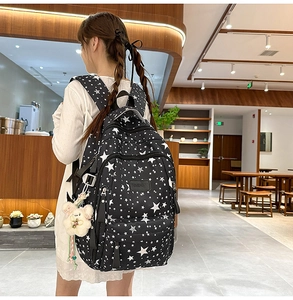 Detail of black backpack with white star print and cute plush rabbit charm accessory