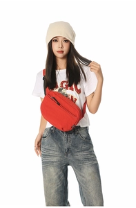 Detail of red nylon crossbody bag with black zipper worn by model in street style