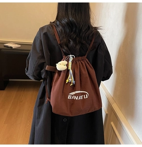 Dunkelbrauner Nylon-Rucksack mit Kordelzug und süßen Plüsch-Anhängern im Detail