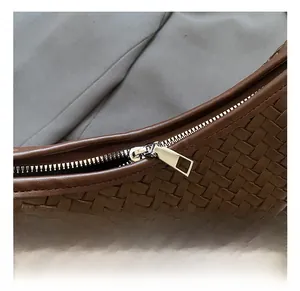 Close-up of dark brown woven handbag featuring a premium silver metal zipper detail
