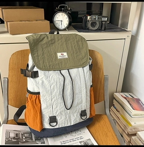 Detail of color-block backpack with wrinkled nylon fabric texture and flap closure