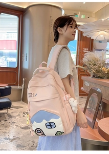 Detailed side view of pink student backpack with cute cartoon house and rabbit plush charm