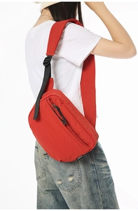 Detail of red minimalist crossbody bag with multi-layer zippers and adjustable nylon strap