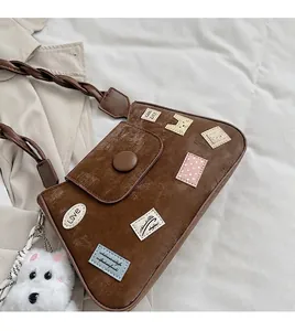 Detalle de bolso retro marrón con parches coloridos y un colgante de perrito de peluche