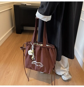 Detail der dunkelbraunen Nylon-Tote-Bag mit weißem Logo und Plüsch-Wolkenanhänger
