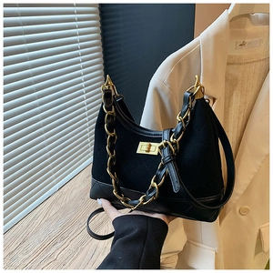 Detail of black quilted texture bag with gold chain and twist lock on a wooden surface