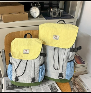 Detailed close-up of color-block nylon backpacks in large and small sizes on a vintage chair