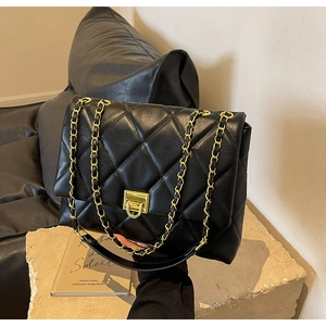 Detailansicht der gesteppten schwarzen Ledertasche mit Goldkette und Drehverschluss