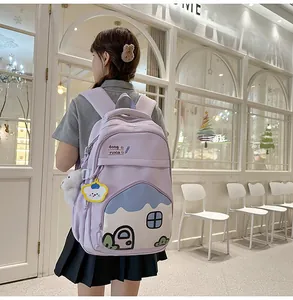 Close-up of a purple school backpack featuring a cute blue cartoon house pocket design