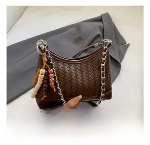 Detail of dark brown woven leather crescent bag with silver chain and colorful wooden beads