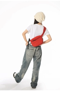 Red multi-compartment crossbody bag worn by a model in a casual street style look.