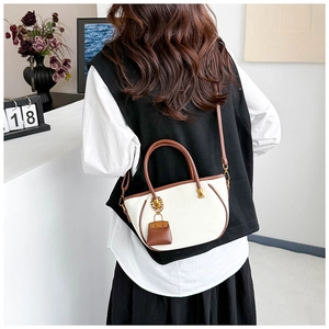 Detail of premium bicolor bucket bag featuring brown handles and mini bag charm