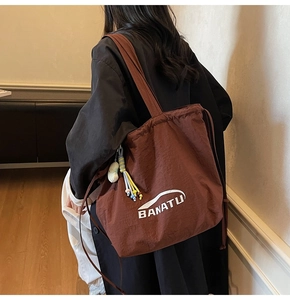 Detail der braunen Nylon-Zugbeuteltasche mit BANATU-Print und bunten Anhängern
