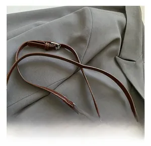 Detail of adjustable leather strap and silver metal buckle on woven shoulder bag