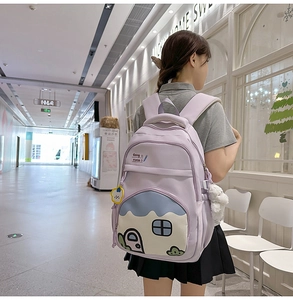Detail of light purple nylon backpack featuring cute cartoon house print and plush charms