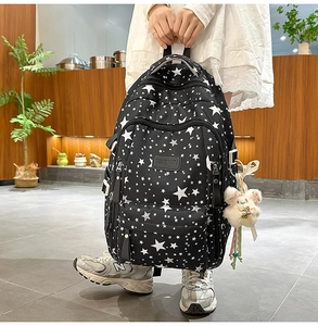 Detail of printed student backpack with star pattern and soft plush doll keychain accessory