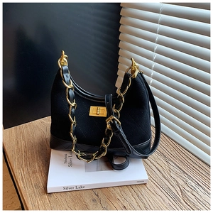 Detail of black quilted hobo bag with gold chain strap and metallic twist lock