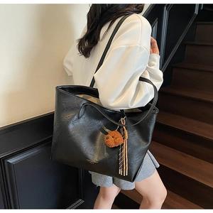 Detail of black PU leather tote bag with gold lettering and cute brown bear pendant