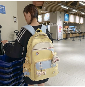 Detail of a bright yellow and blue student backpack with cute patches and plush charms