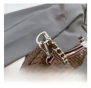 Detail of dark brown woven leather handbag featuring a polished silver metal chain strap