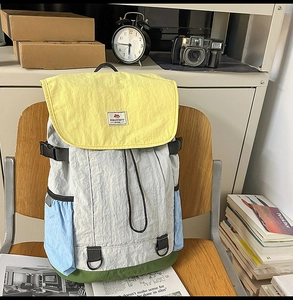 Detail view of colorful nylon backpack with drawstring and buckle on a wooden chair