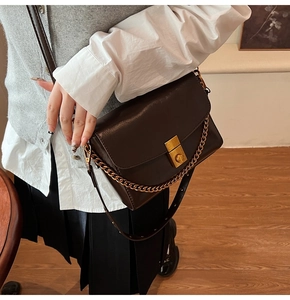 Détail du sac bandoulière en cuir marron foncé avec chaîne dorée et fermoir vintage