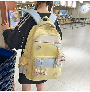 Detail view of the yellow canvas backpack featuring cute panda and cat plush charms
