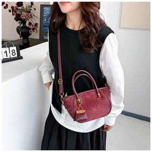 Close-up of burgundy frosted suede handbag with detachable mini pouch charm and strap
