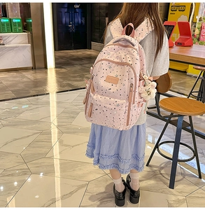 Rear view of pink starry backpack with multiple pockets and plush pendant on person