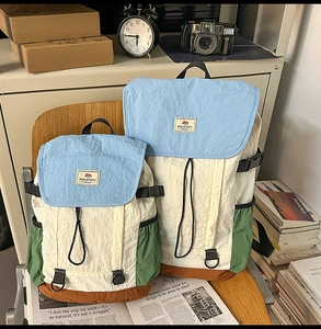 Two patchwork backpacks in cream, light blue and green on a wooden chair with vintage props