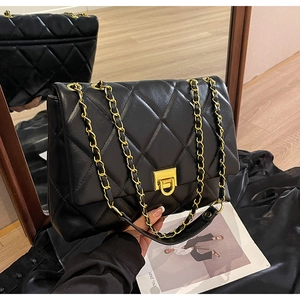 Detail der schwarzen Stepptasche mit goldener Kette und metallischem Drehverschluss