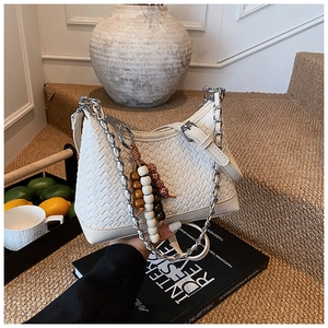 Detailed view of white woven leather texture with silver chain and wooden bead charm
