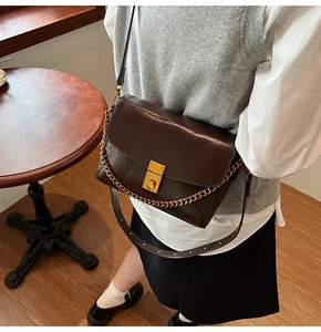 Détail du sac bandoulière vintage en cuir marron foncé avec chaîne dorée et boucle