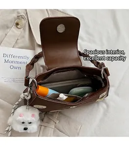 Vista detallada del interior de bolso de hombro marrón con colgante de perro y logotipo