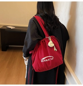 Detailansicht der roten Canvas-Beuteltasche mit weißem Logo und Plüsch-Mondanhänger