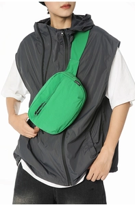 Detail of green nylon crossbody chest bag with wide strap and zip on male model