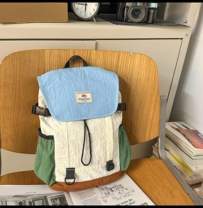 Detail of color-block nylon backpack featuring wrinkled texture and buckle closure details