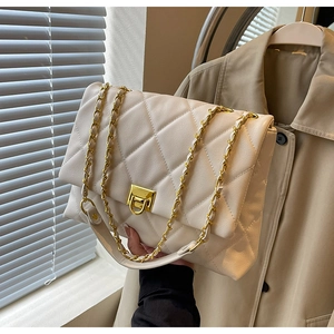 Detail of quilted beige leather bag with a gold chain strap and square metal lock clasp