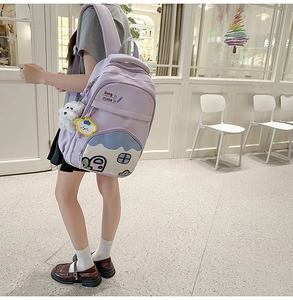Side view of a light purple student backpack with a house patch and plush dog pendant