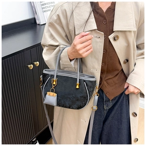 Detail of minimalist black velvet handbag with grey handle and gold metal hardware