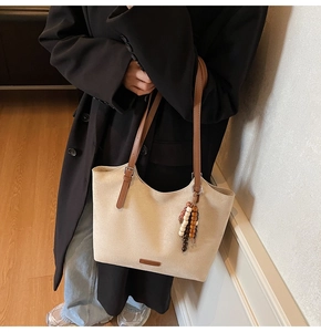 Minimalist beige suede tote bag with brown straps and bohemian bead tassel detail