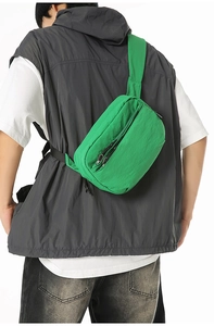 Detail of lime green crossbody bag showing nylon crinkle texture and zipper compartments