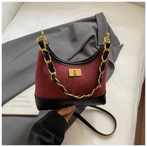 Detailed view of burgundy suede and black leather stitching with gold turn-lock closure