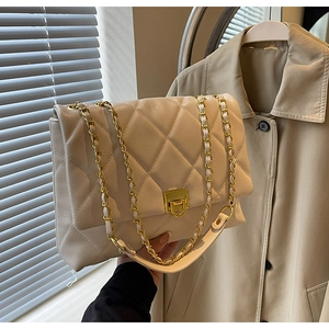 Detail der gesteppten cremefarbenen Ledertasche mit eleganter Goldkettentextur